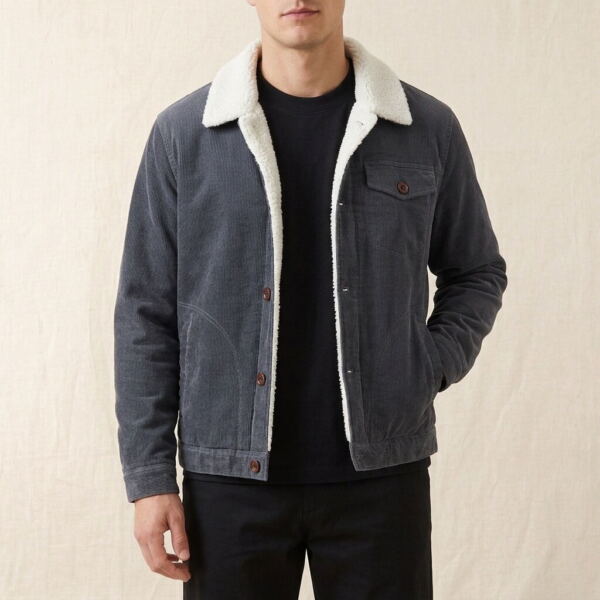 Man wearing an open dark grey sherpa-lined corduroy jacket over a black tee and black trousers